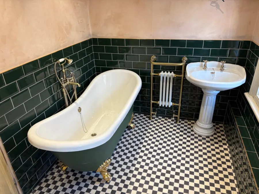 Period-style bathroom with green metro tiles and freestanding bath