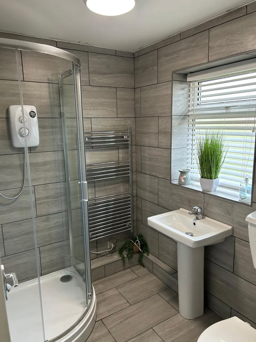 Grey tiled shower room with corner shower enclosure