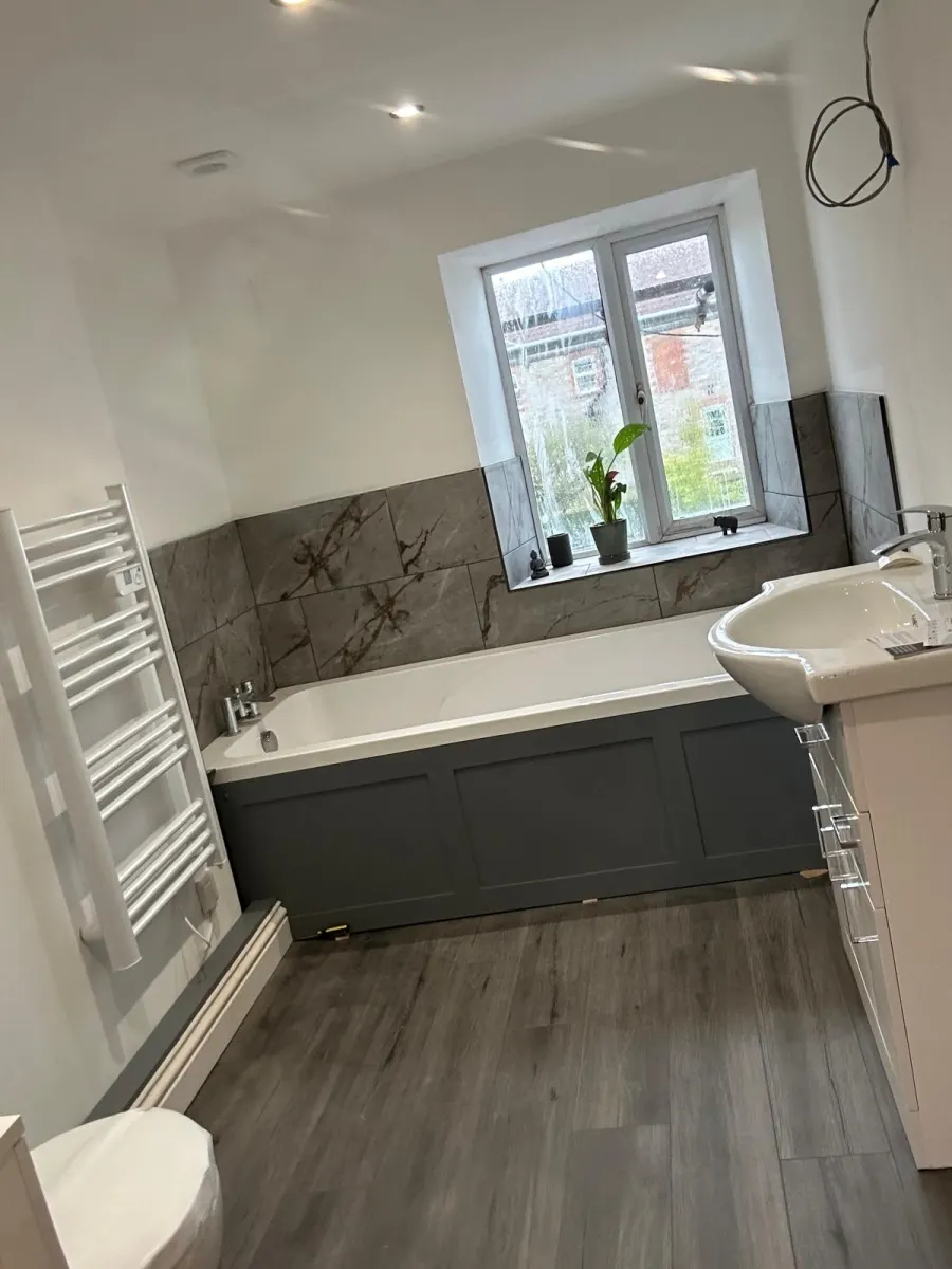 En-suite with charcoal bath panel and marble-effect tiling