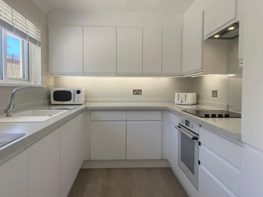 Light grey shaker kitchen with brass hardware and quartz splashback