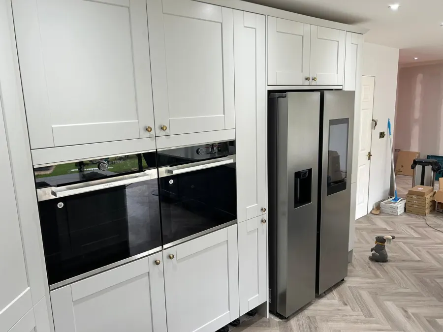 Fitted kitchen with tall units, integrated fridge freezer and herringbone flooring